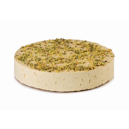 Disco redondo de halva claro cubierto con pistacho picado, textura densa y desmenuzable, sobre fondo blanco.