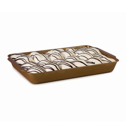 Filas de pasteles con glaseado blanco y líneas de chocolate negro, en una bandeja dorada rectangular