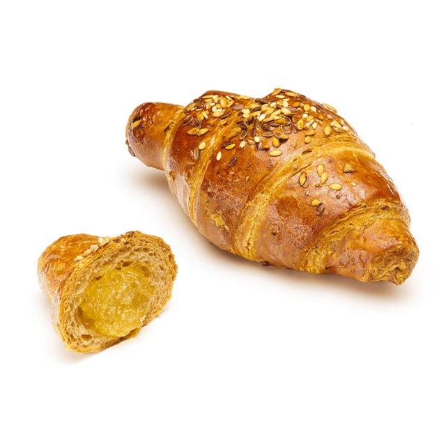 Croissant multicereales dorado cubierto de semillas, con un trozo cortado que revela un relleno amarillo suave, sobre...