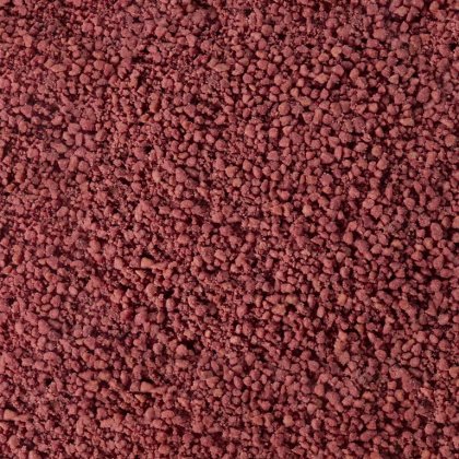 Textura de gránulos o polvo grueso marrón rojizo, similar a granos minerales o especias apelmazados.