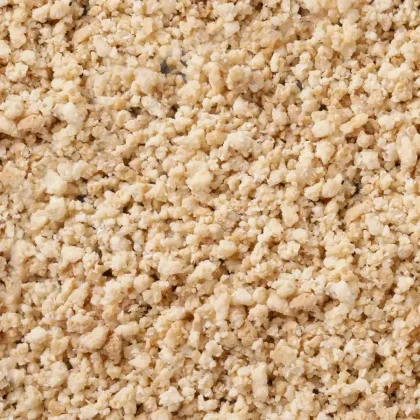 Primer plano de gránulos beige claro desmenuzables con textura gruesa tipo migas que cubren todo el encuadre