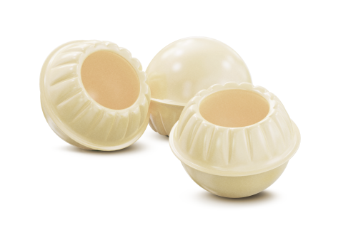 Tres cáscaras redondas de chocolate blanco con bordes rizados, dos huecas, sobre fondo blanco.